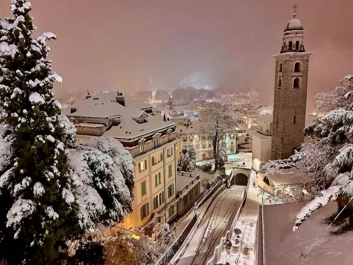 The city of Lugano in Switzerland blanketed in snow at night.